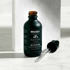 Hands applying Brickell Men's Argan Oil for smooth, manageable hair.