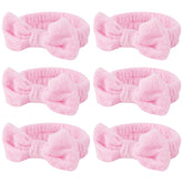 Casoty pink spa headband with bow keeps hair away during skincare.
