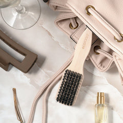 EcoTools Mini Slick Back Brush in hand demonstrates precise control for sleek styles.