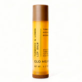 Bálsamo labial Glo Melanin con limón y cúrcuma en envase, brillo suave natural.