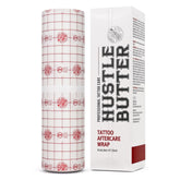 Hustle Butter Second Skin Wrap shown during wrap application on a fresh tattoo, protecting healing skin