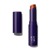 Keys Soulcare Balsamo labial tintado Bronze Aura en empaque compacto para llevar.