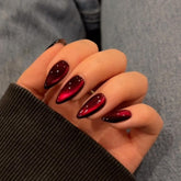 Uñas KQueenest rojas oscuras con brillo y efecto ojo-gato para looks nocturnos.