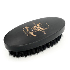 Menesia pocket-travel beard brush shown beside a phone for on-the-go grooming.