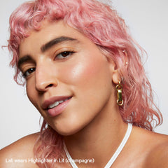 Milk Makeup Lit highlighter stick on shoulders for body radiance.