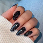 Modelones uñas falsas en forma almendra con brillo negro para un look rápido.