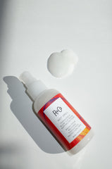 R+Co Hot Spell balm being spread into smoothing cream for frizz control