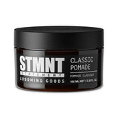 STMNT Grooming Goods Classic Pomade bottle close-up showing natural shine and strong hold.