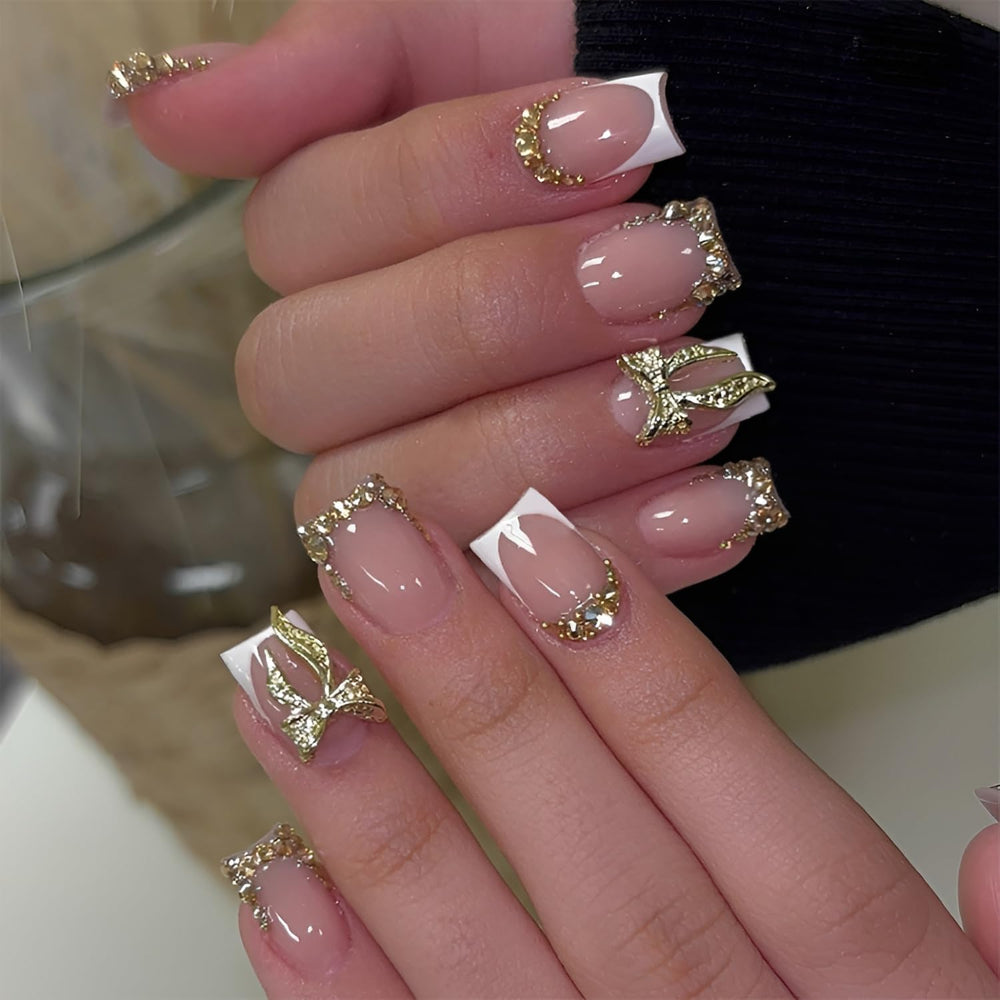 Uñas Tnbuokas con puntas francesas cortas y lazo dorado para un look elegante.