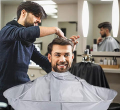 TUEQE deep groove hair catcher on cape in action catching clippings.