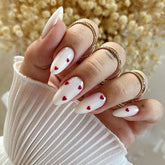 Uñas postizas YEFIUO, forma almendra blanca con detalle de corazón rojo.