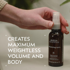 Applying Aveda Volumizing Hair Tonic to damp hair for lift