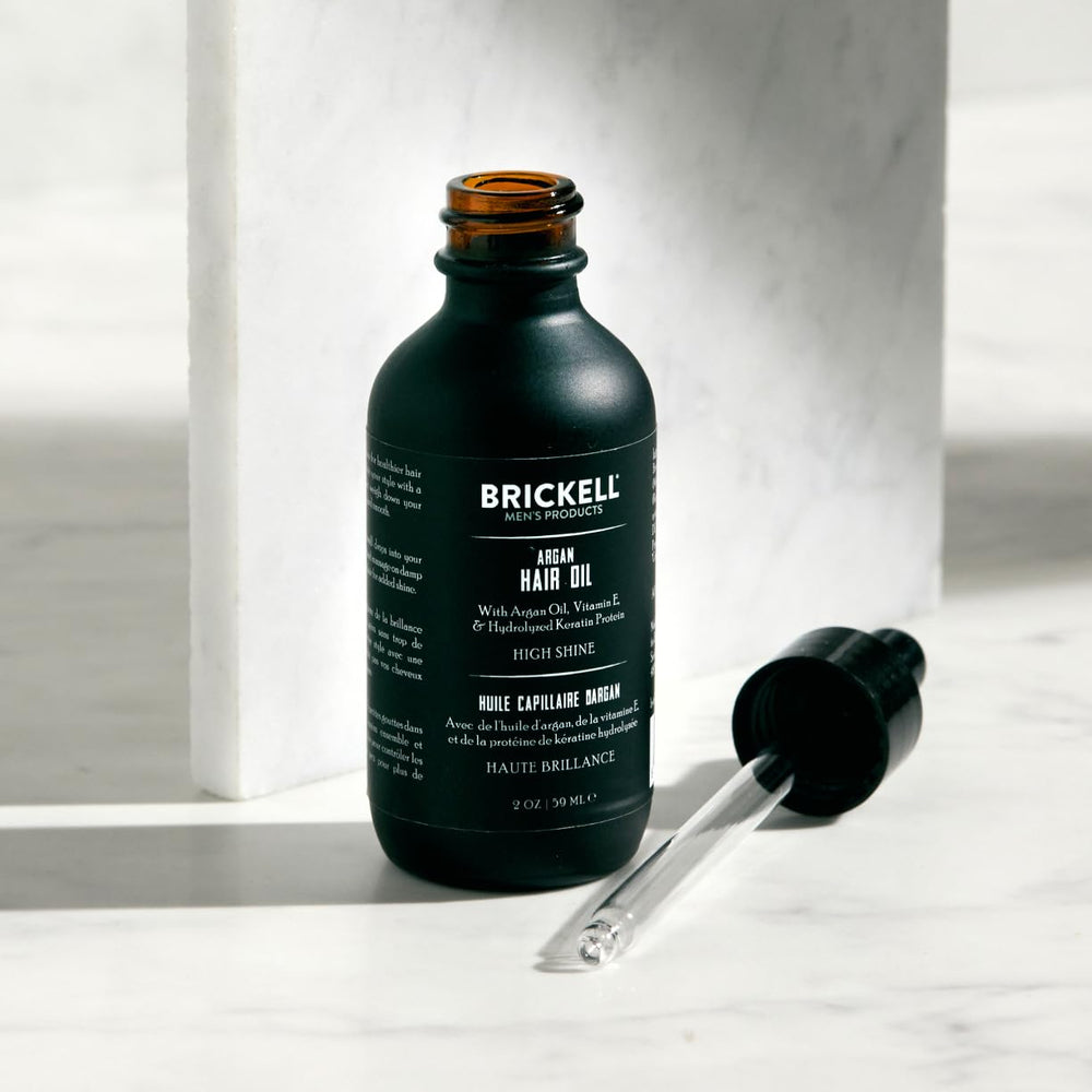 Hands applying Brickell Men's Argan Oil for smooth, manageable hair.