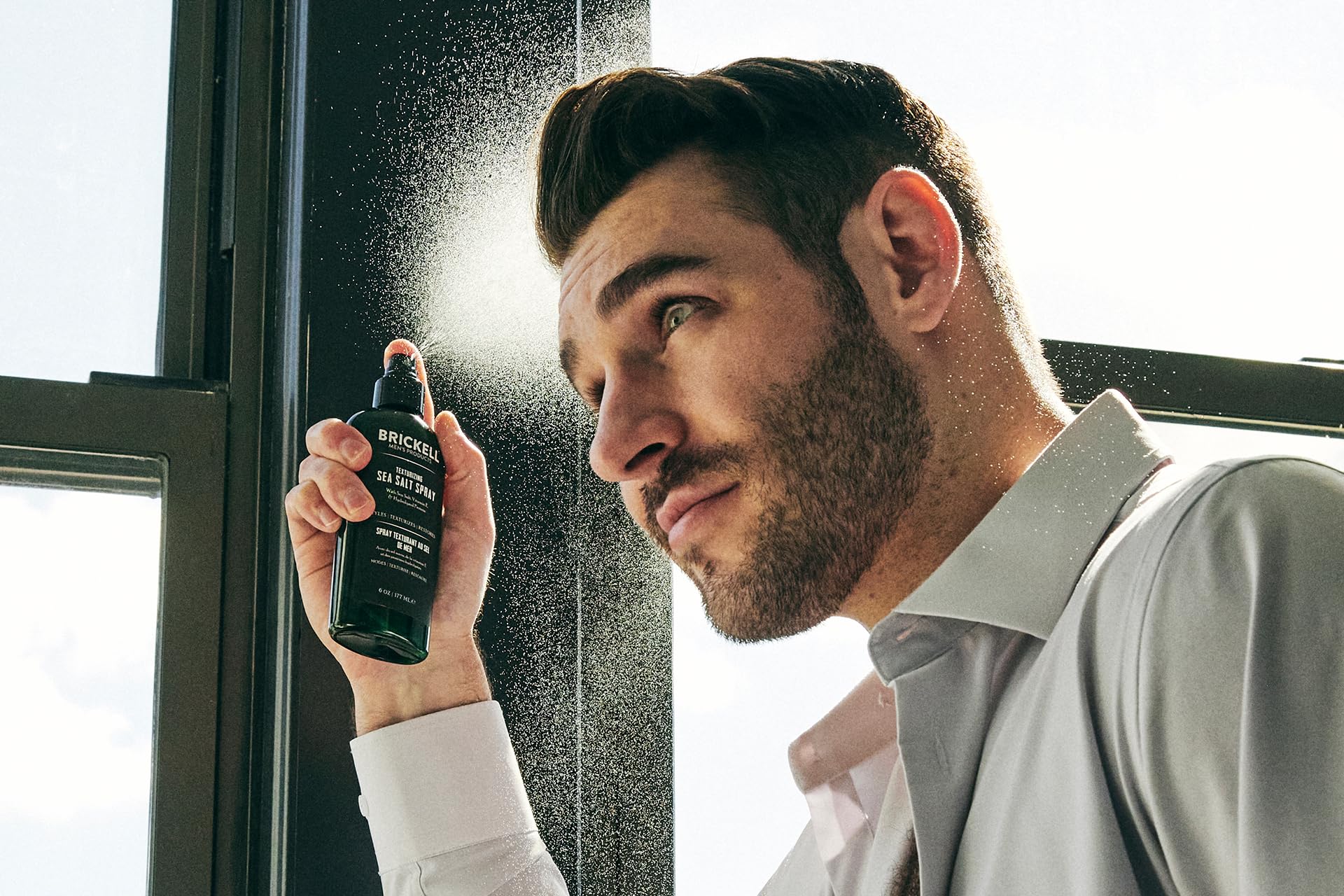 Man with sun-kissed hair demonstrating beachy finish from Brickell spray.