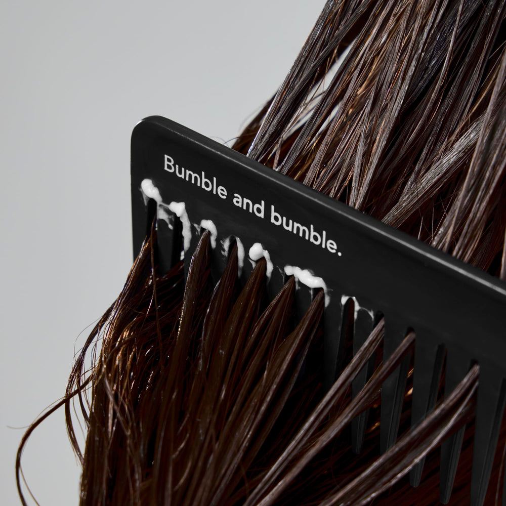 Applying Bumble and bumble Super Rich conditioner to damp hair for detangling.