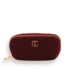 Charlotte Tilbury medium travel makeup bag in quilted velvet with three compartments for organized travel.