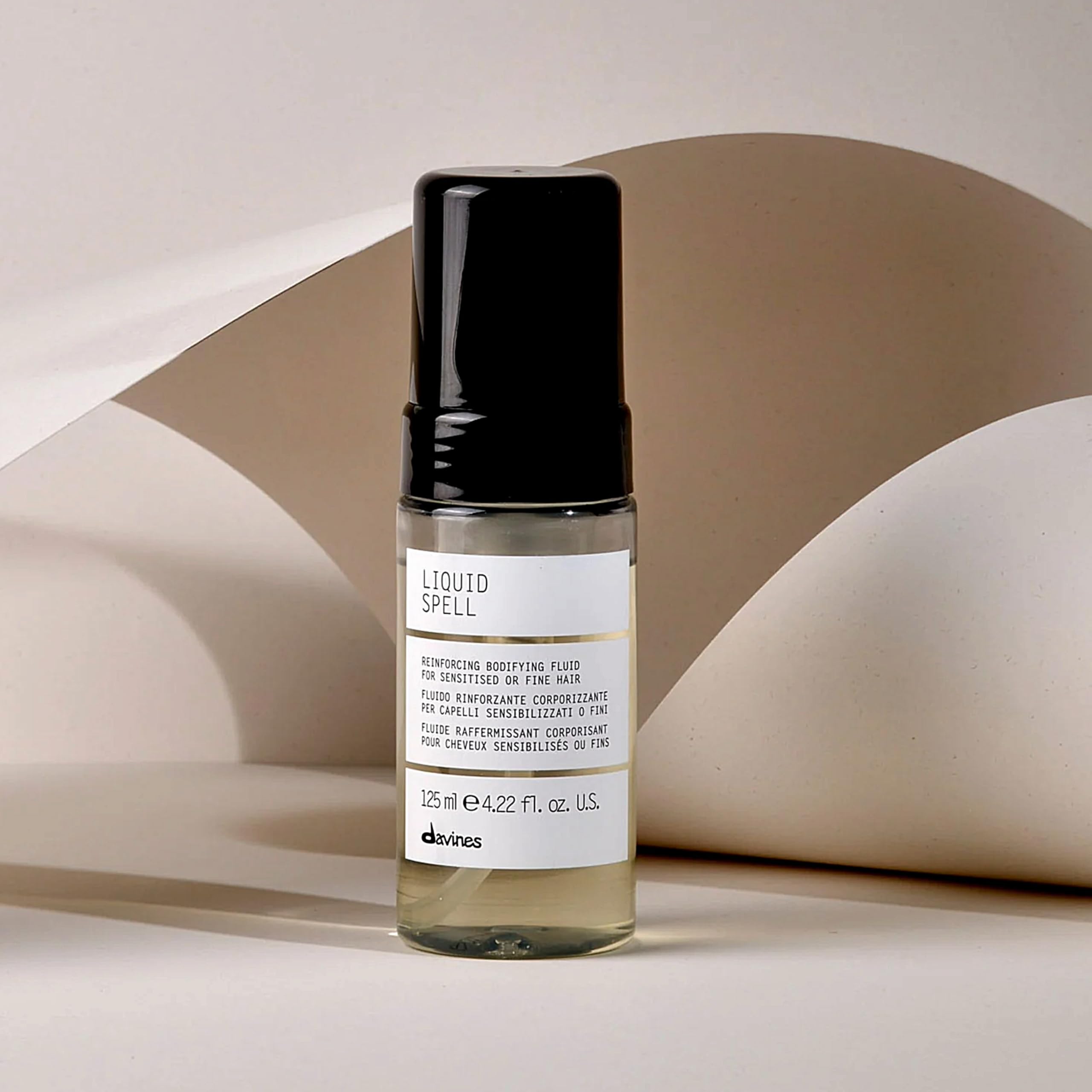 Hands applying Davines Liquid Spell for smooth, even distribution.