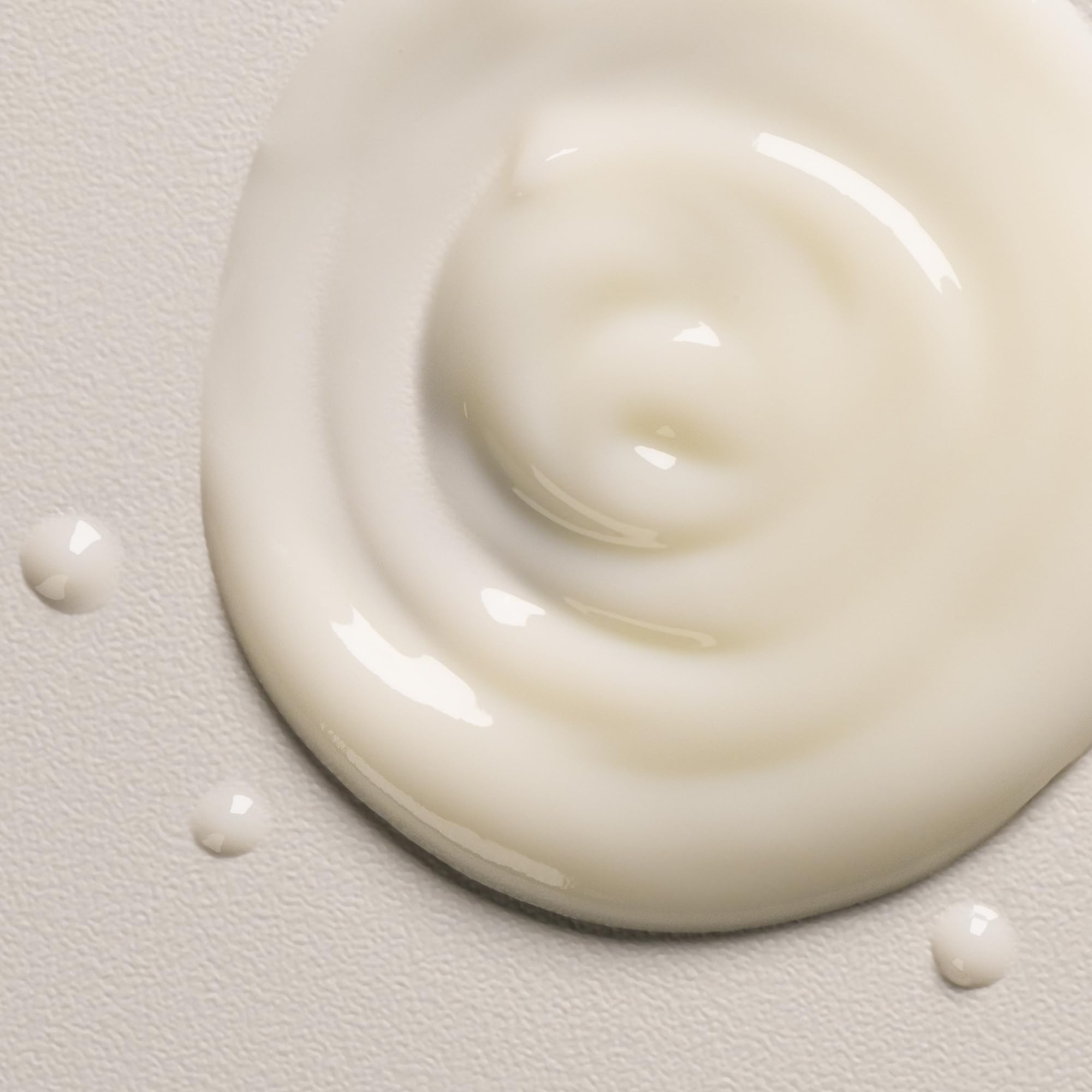 Hands applying the spray to mid-lengths for frizz control