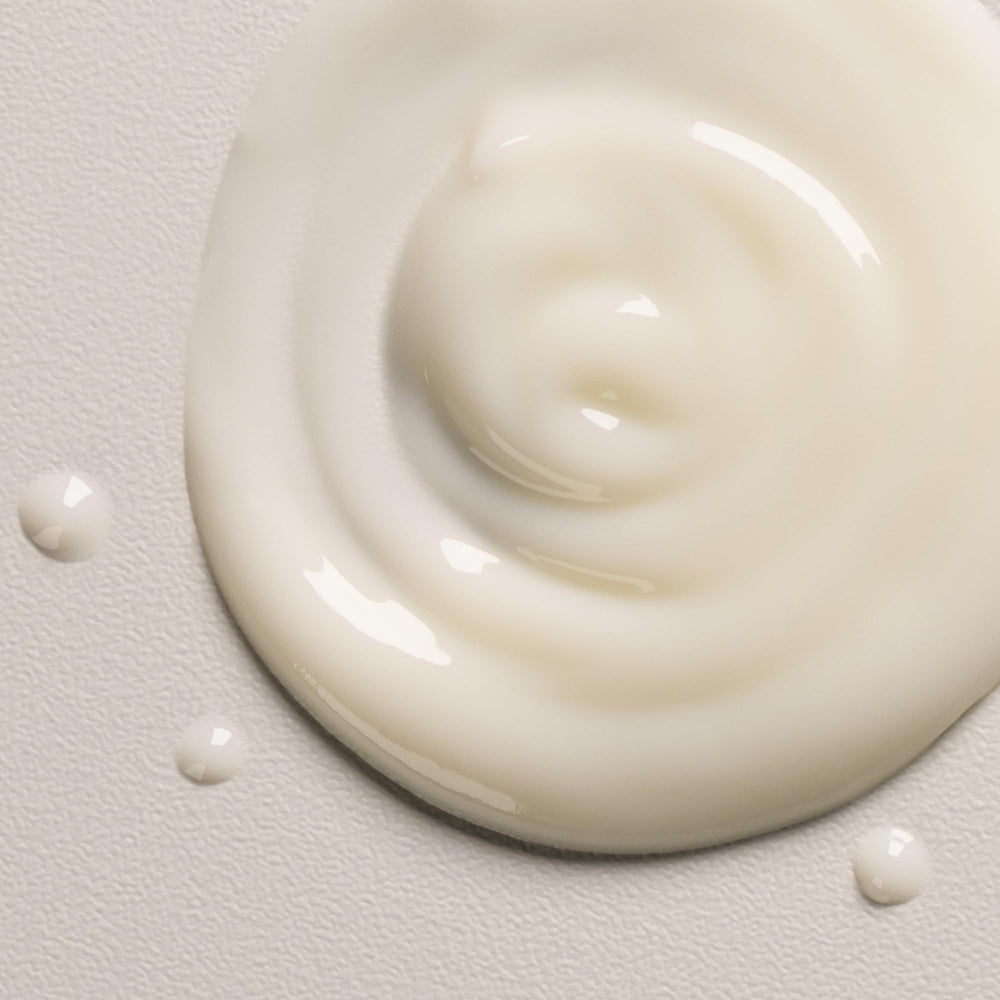 Hands applying the spray to mid-lengths for frizz control
