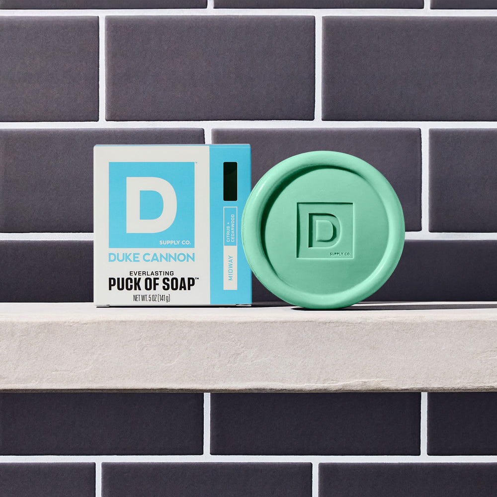 Duke Cannon Midway soap puck in shower shelf highlighting long-lasting 5oz bar.