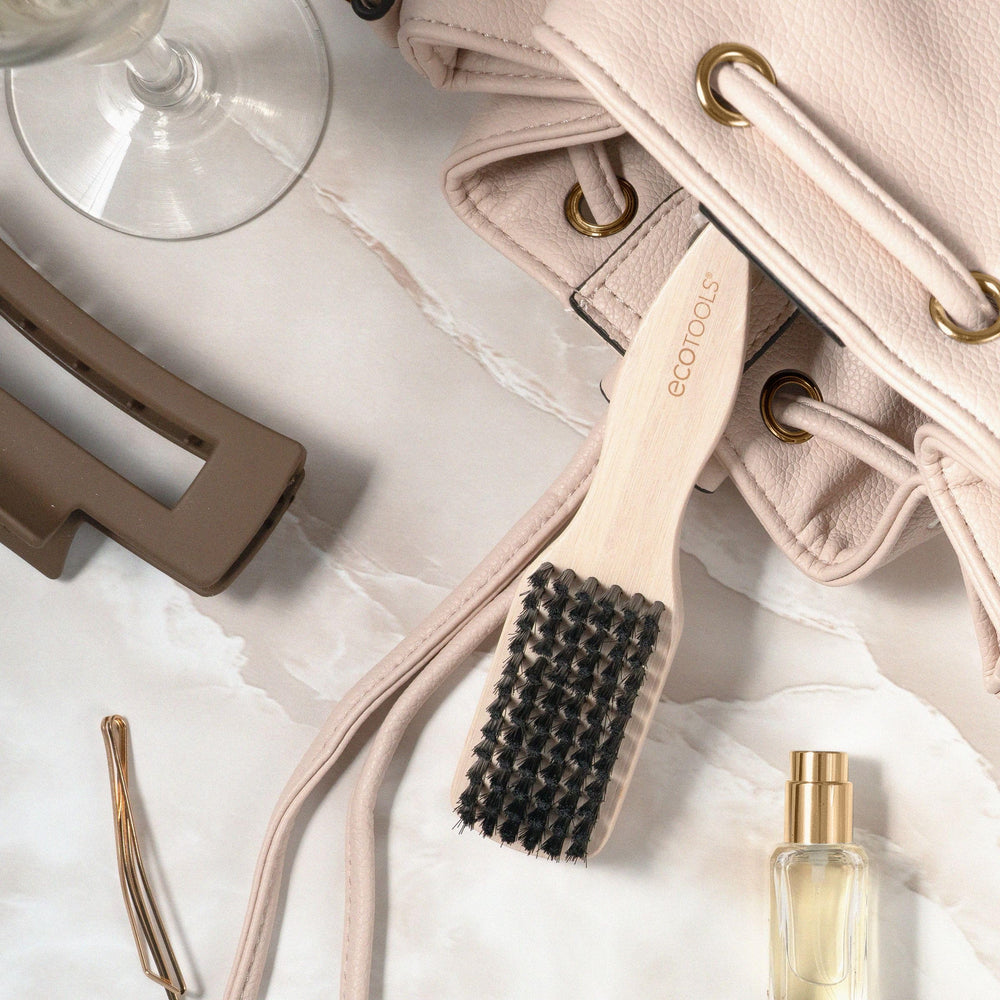 EcoTools Mini Slick Back Brush in hand demonstrates precise control for sleek styles.