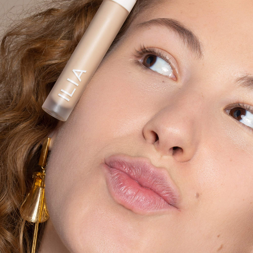 Applying ILIA True Skin Serum Concealer for precise coverage around dark circles.