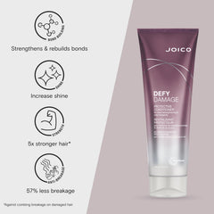 Hands applying Joico Defy Damage conditioner through mid-lengths for smooth, color-safe hair