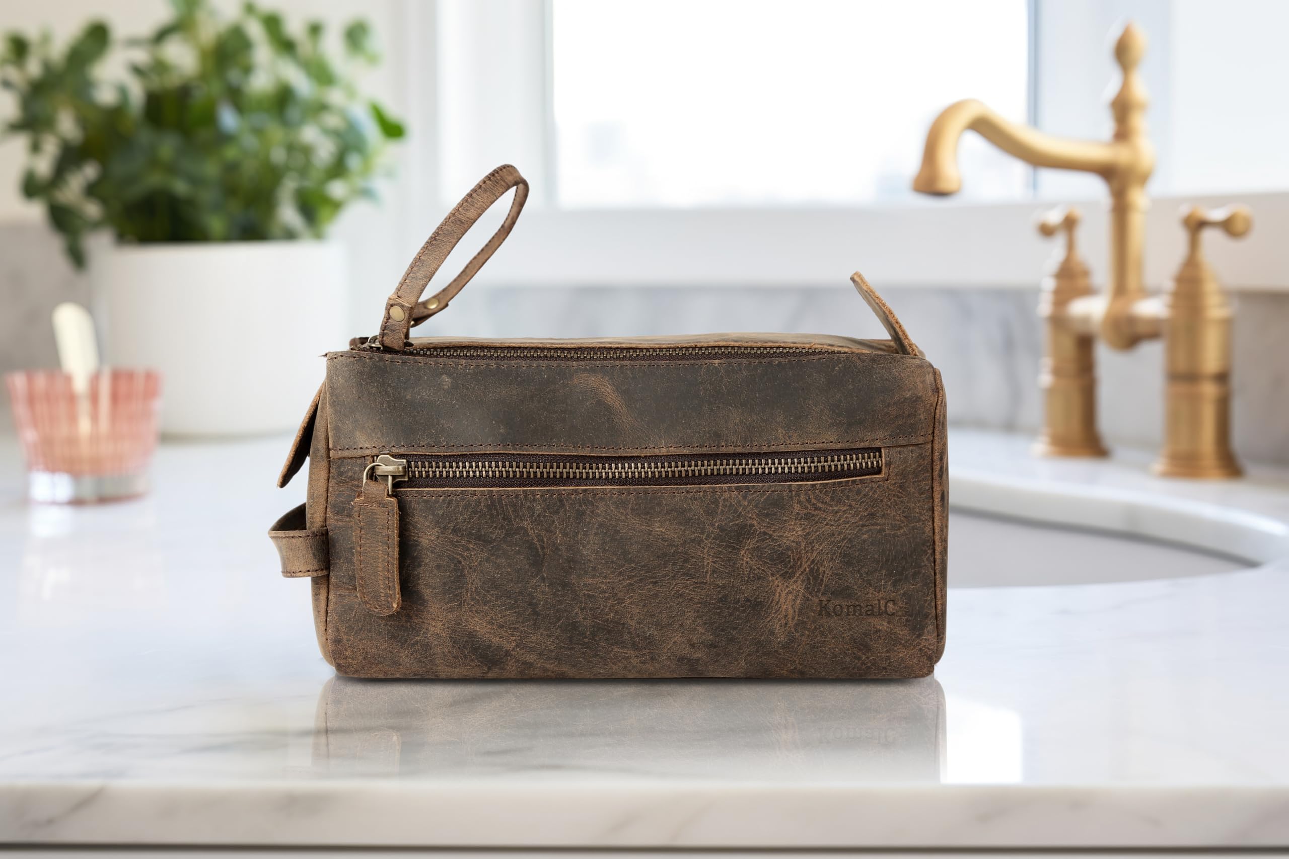 KomalC travel-ready buffalo leather toiletry bag shown beside luggage for jet-set appeal.