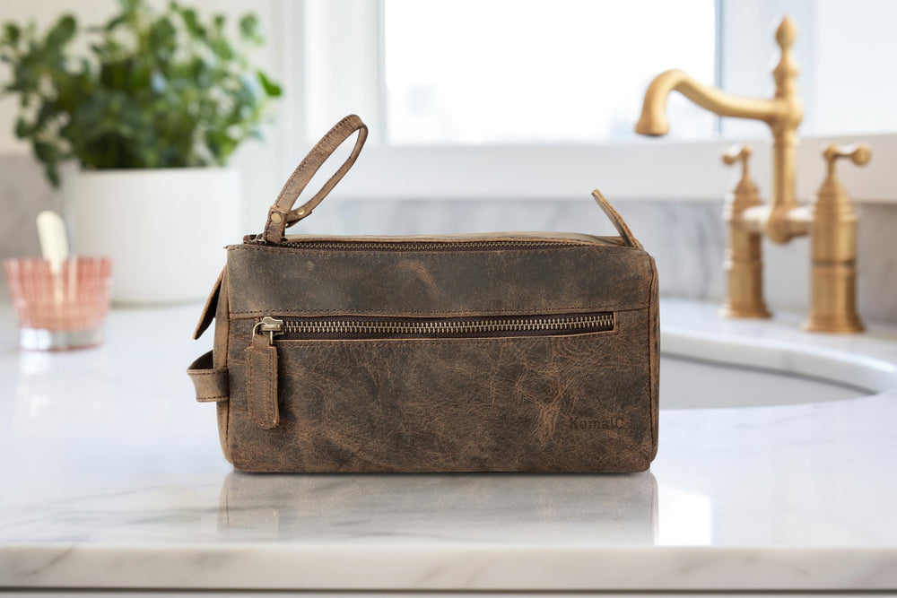 KomalC travel-ready buffalo leather toiletry bag shown beside luggage for jet-set appeal.