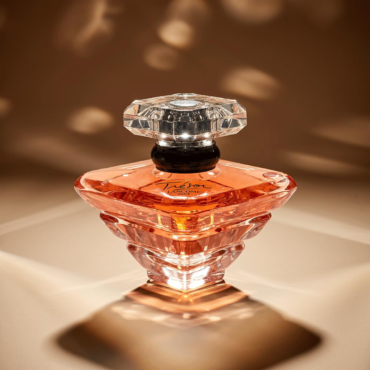 Lancôme Trésor bottle bathed in soft light suggesting romantic wear.