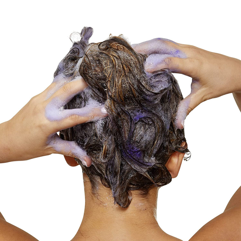 Pouring L'Oréal Professionnel Paris purple shampoo into hand for easy application.