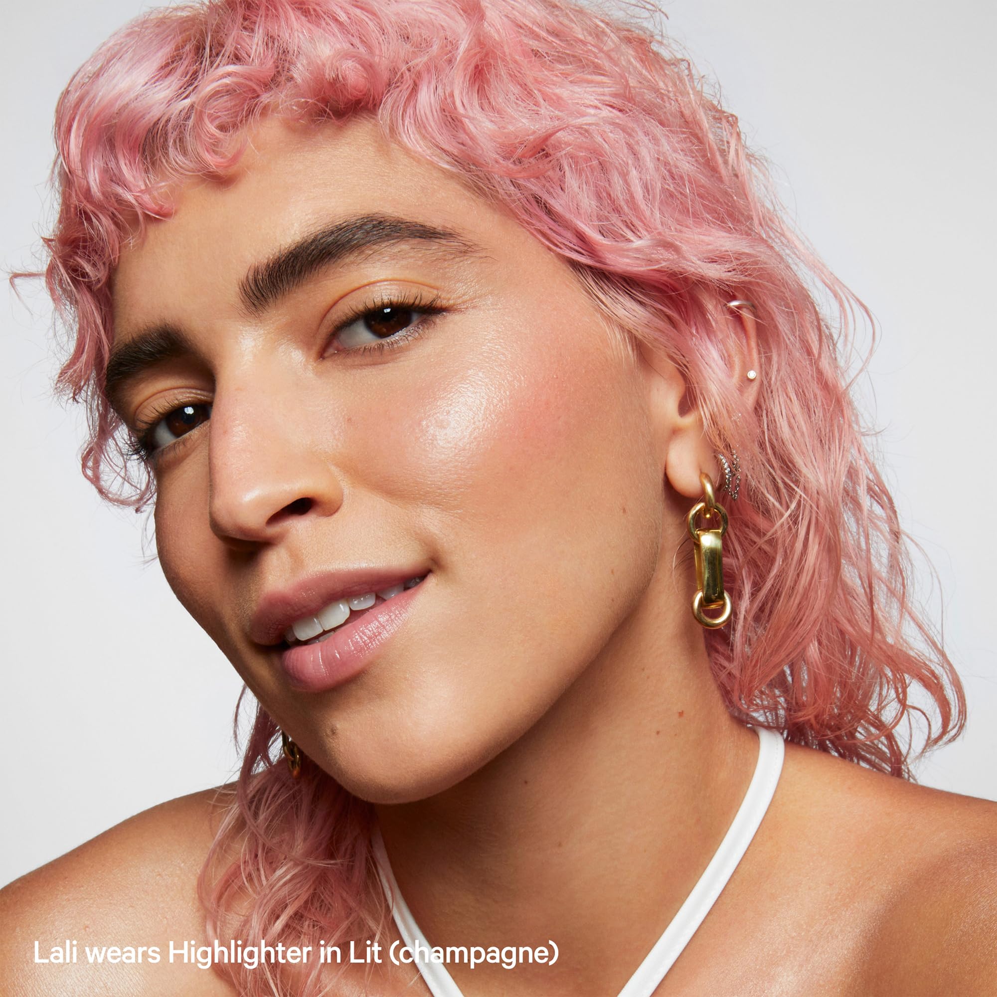 Milk Makeup Lit highlighter stick on shoulders for body radiance.