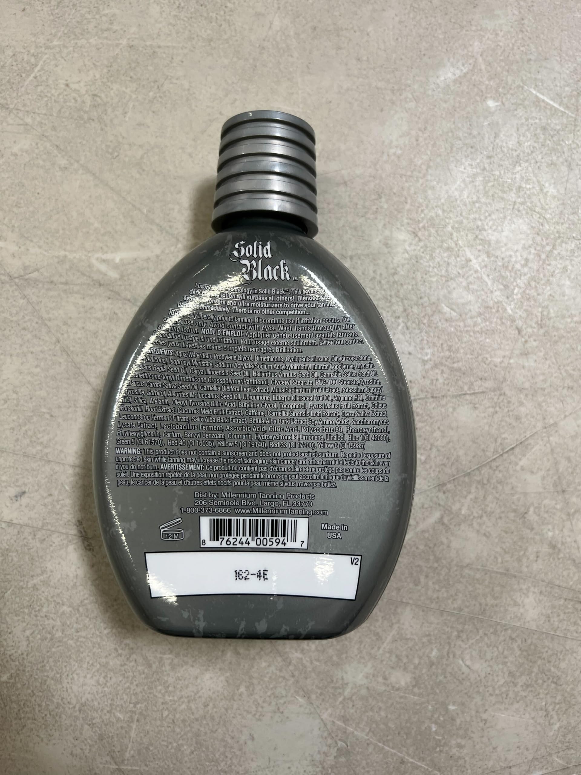 Millennium Tanning Solid Black 100X 13.5fl oz bottle on shelf.