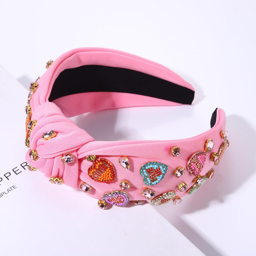 MOLOCH pink heart headband with crystal embellishments adds subtle sparkle.