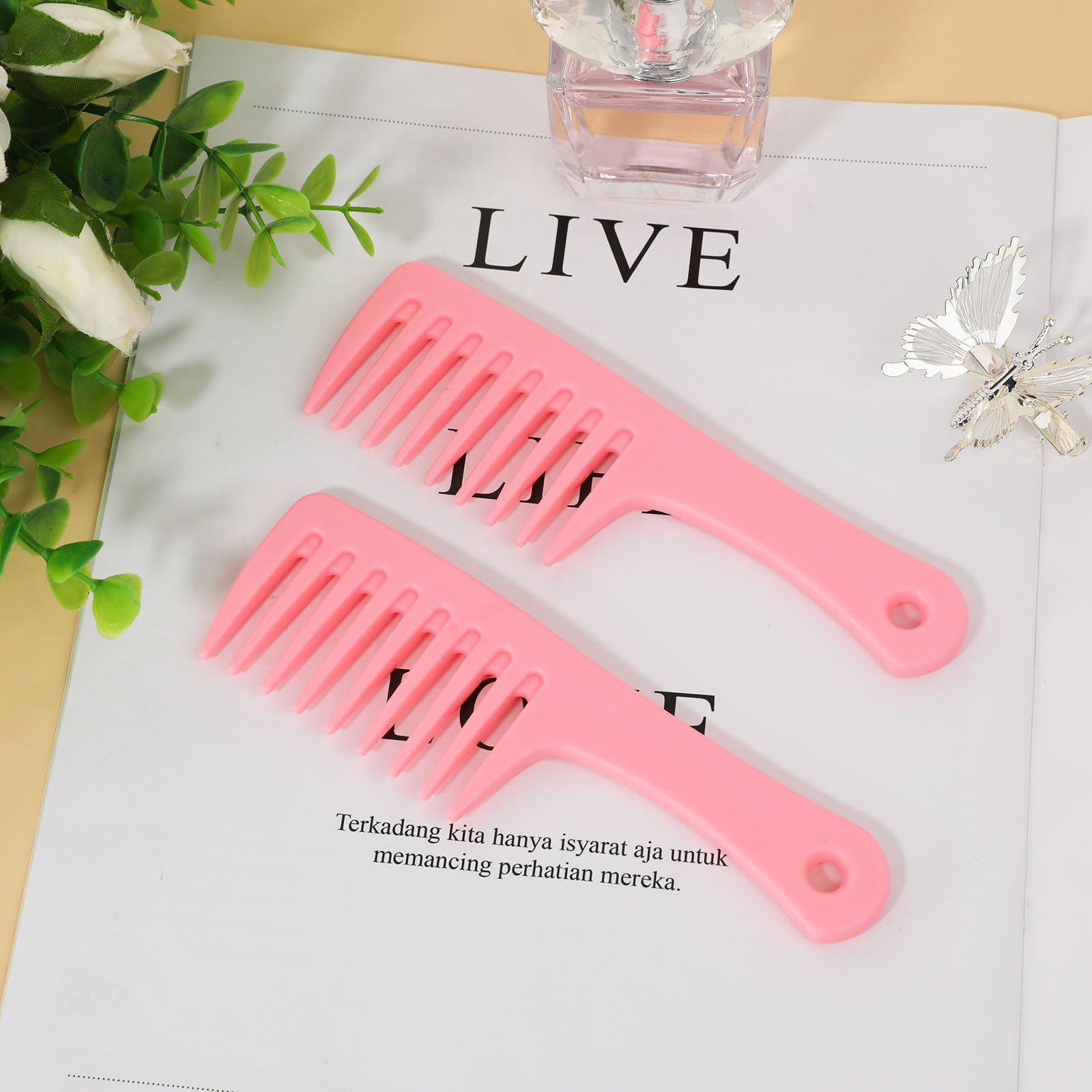 Mozeat Lens travel-size pink detangling comb held for on-the-go grooming.