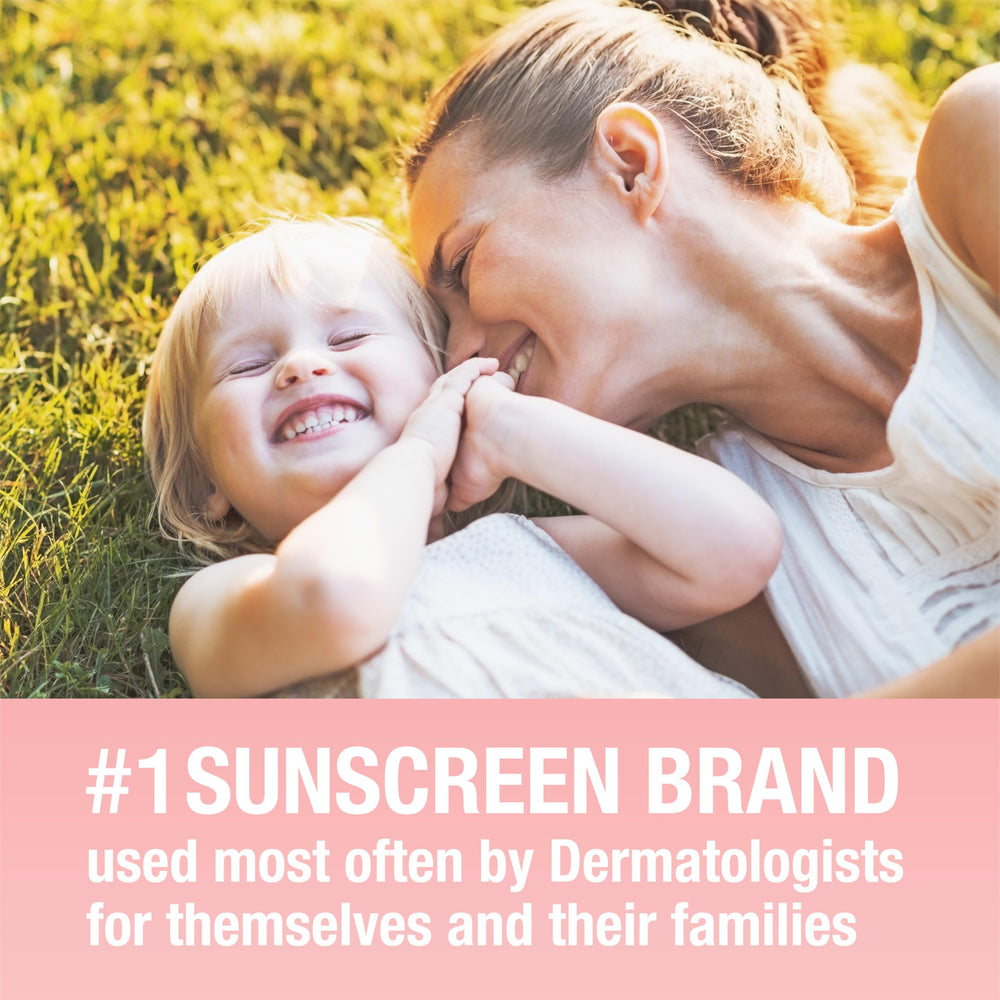 Applying Neutrogena Pure & Free sunscreen on baby's arm outdoors.
