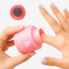 Person dipping finger into Olive & June remover pot for manicure.