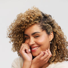 Applying Paul Mitchell Clean Beauty Anti-Frizz Conditioner on textured hair for manageability