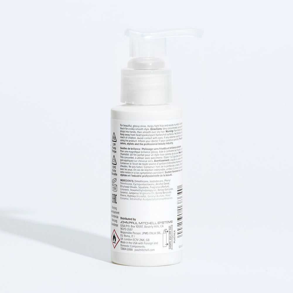 Paul Mitchell Gloss Drops on shelf beside styling tools for shine.