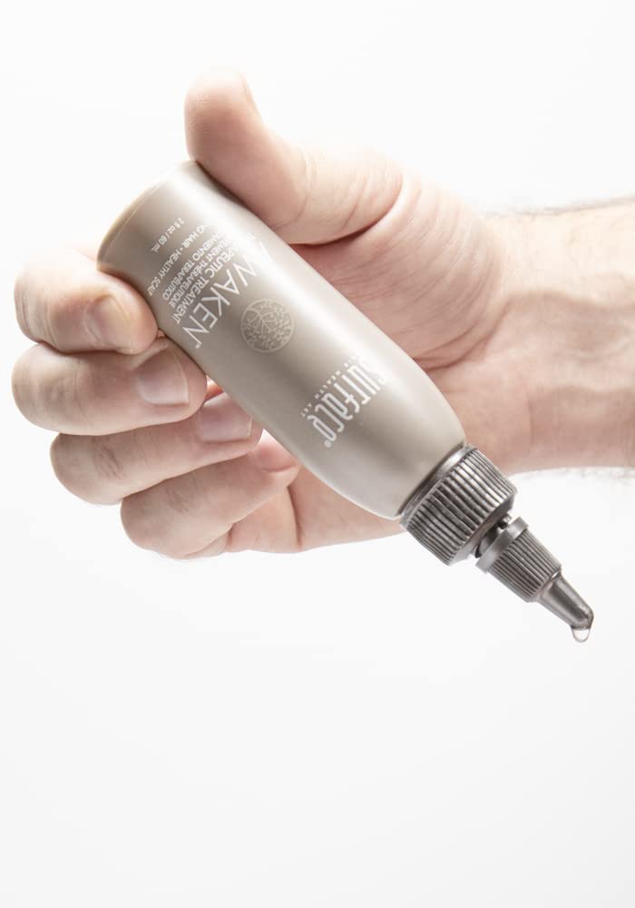 Surface Awaken Therapeutic Treatment bottle shown near a blow-dryer, suggesting heat styling compatibility.