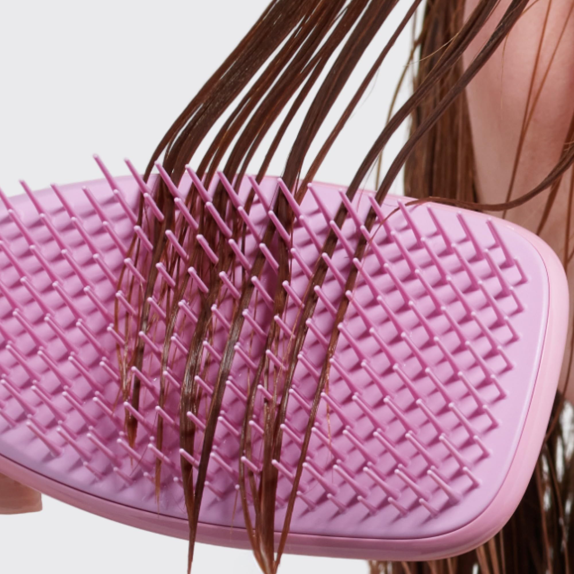 Tangle Teezer Ultimate Detangler displayed with conditioner bottle for even distribution.