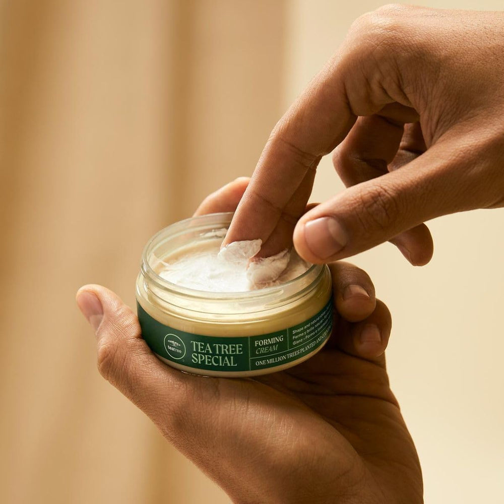 Hands applying Tea Tree Forming Cream to style hair with texture.