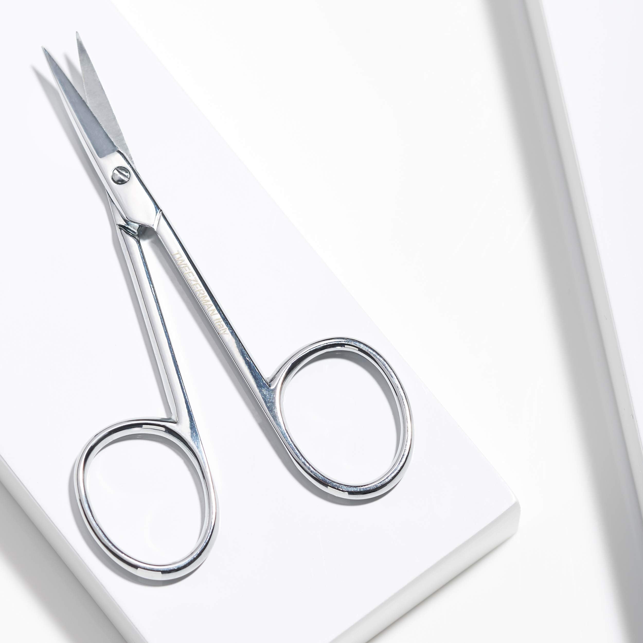 Tweezerman Cuticle Scissors being cleaned with an alcohol wipe after use.