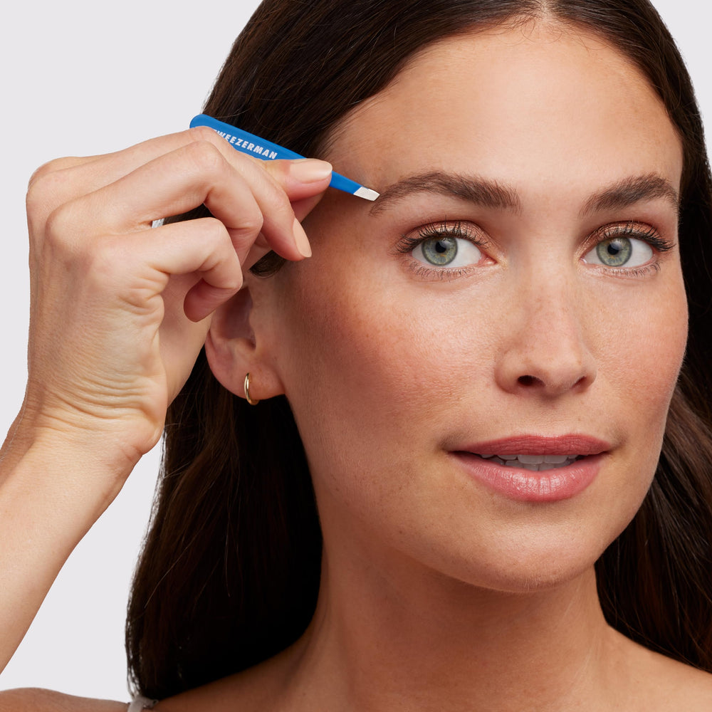 Tweezerman Mini Slant Bahama Blue held in hand for easy grip and control.