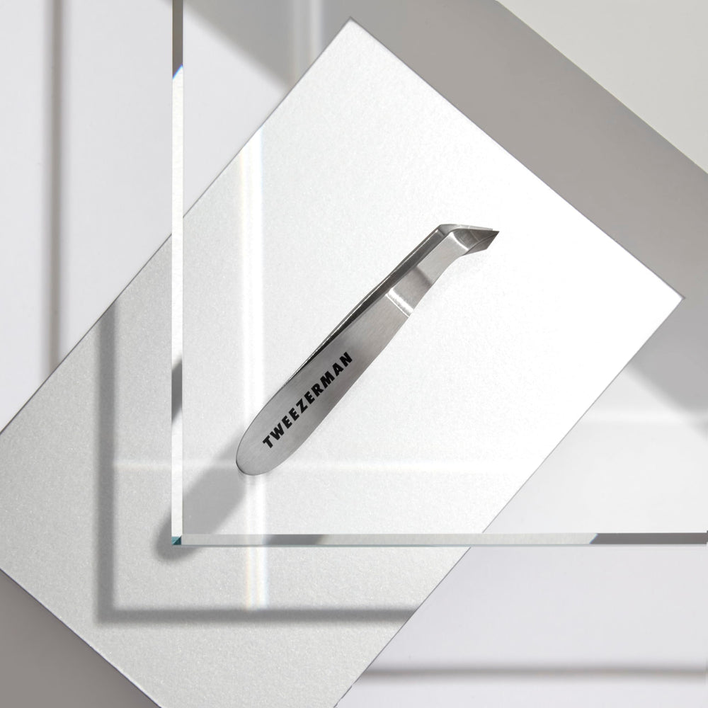 Tweezerman Mini Squeeze Cuticle Nipper beside travel case for on-the-go grooming.