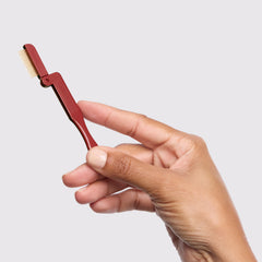 Tweezerman iLashcomb with gold teeth gliding through lashes for clean separation