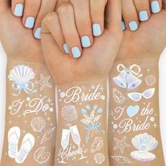 xo, Fetti seashells and wedding bells tattoos on the wrist for coastal glow in photos.