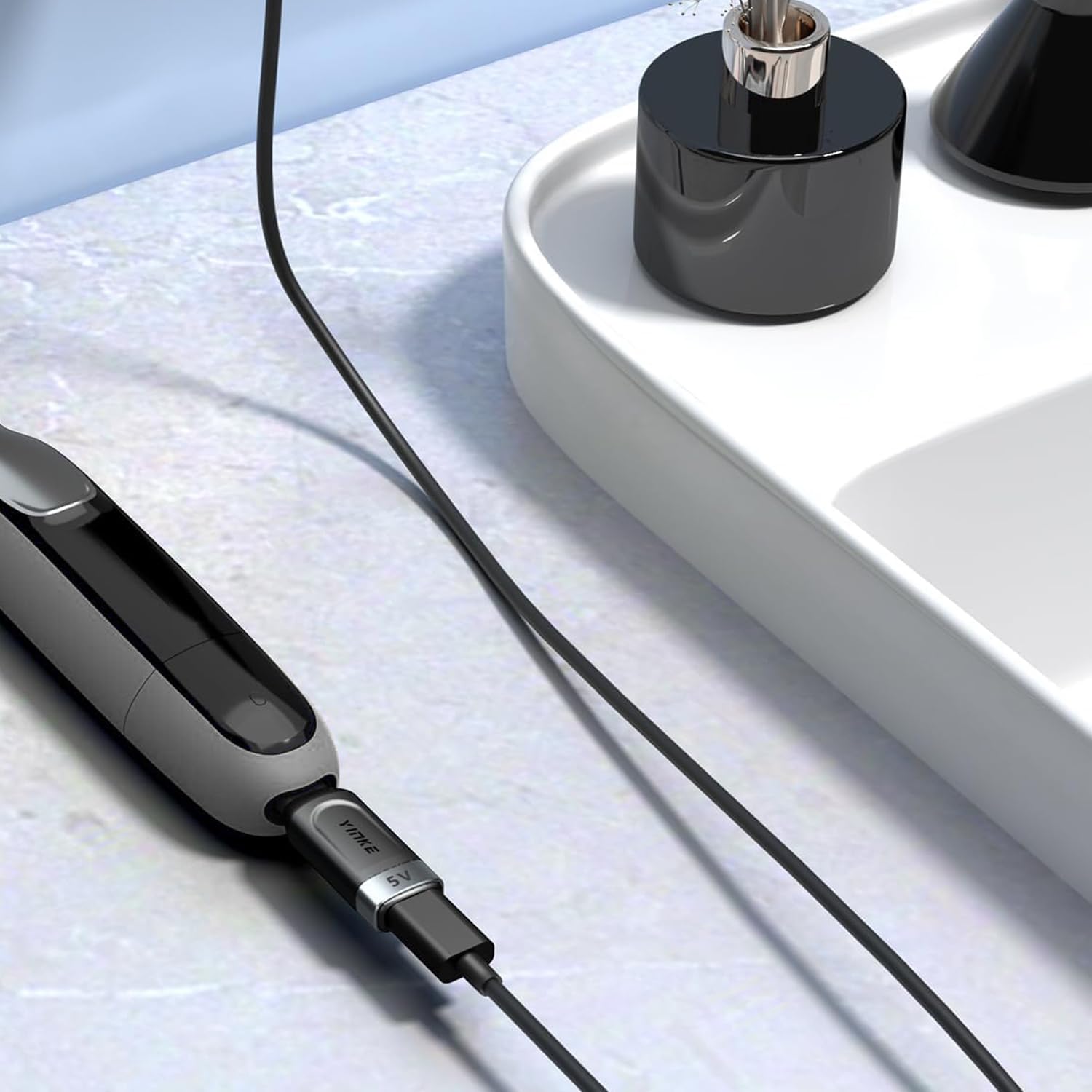 Sleek silver Yinke adapter resting on a travel bag for on-the-go grooming.
