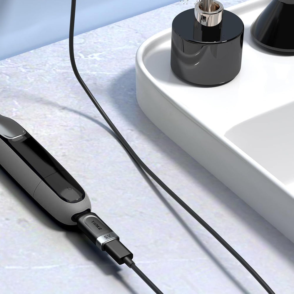 Sleek silver Yinke adapter resting on a travel bag for on-the-go grooming.